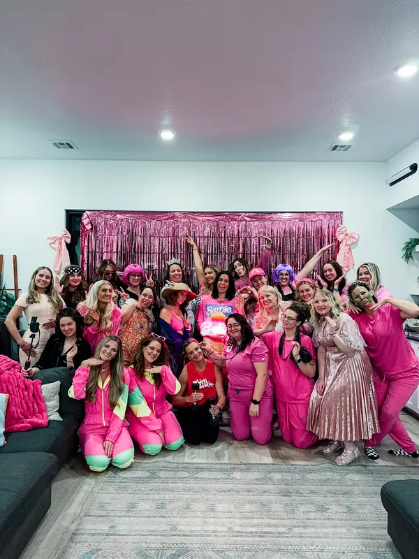 Bestie Squad women dressed in pink at a themed party, posing in front of a sparkly backdrop.
