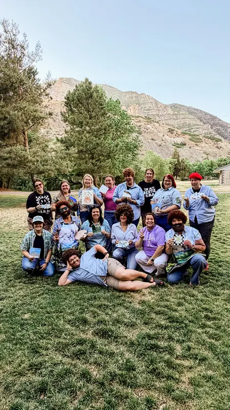 Bestie Squad members in matching costumes holding up their paintings outdoors.